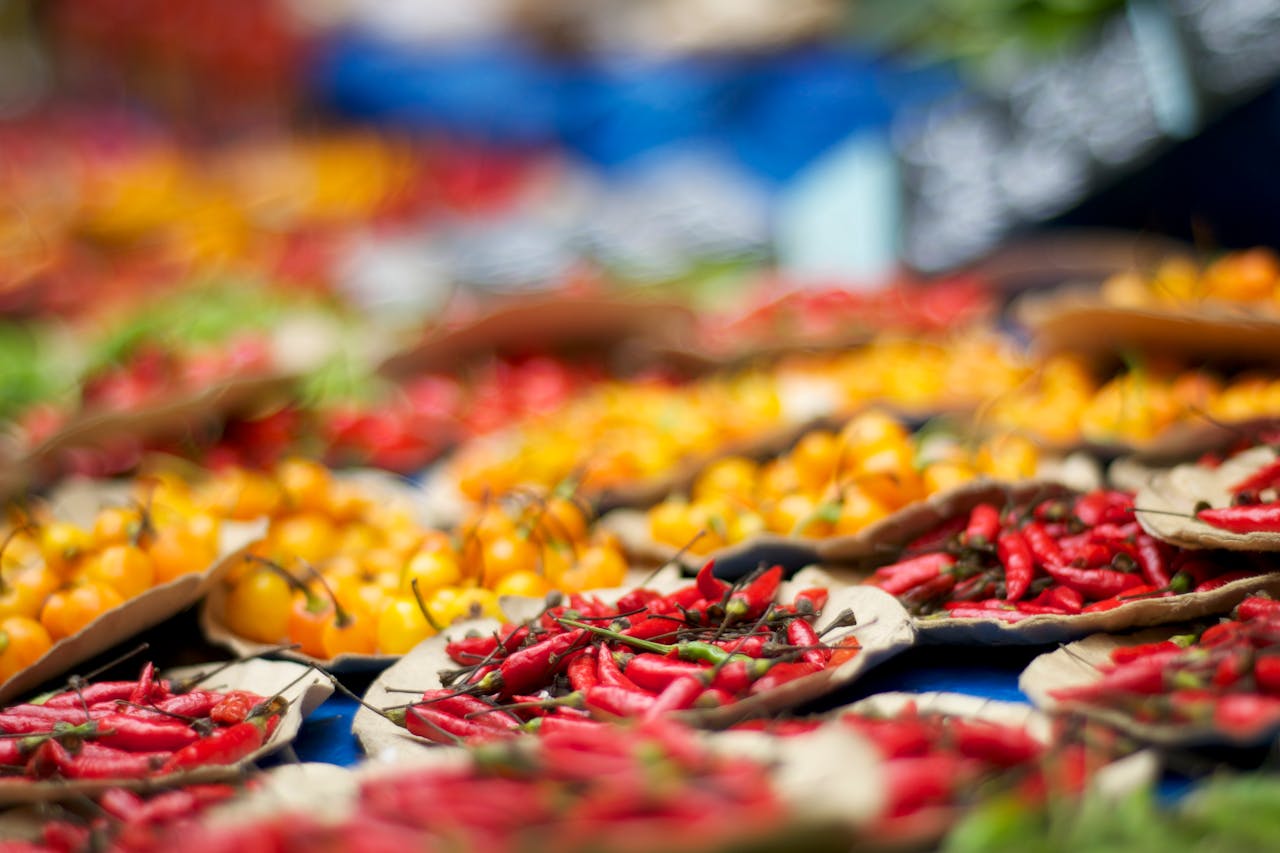 Colorful display of red and yellow peppers at an outdoor market, showcasing fresh organic produce.